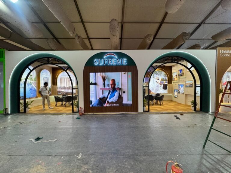 SUPREME exhibition stall featuring elegant arched entrances, illuminated branding, digital LED display, premium interiors, and modern exhibition booth decoration at a trade show.