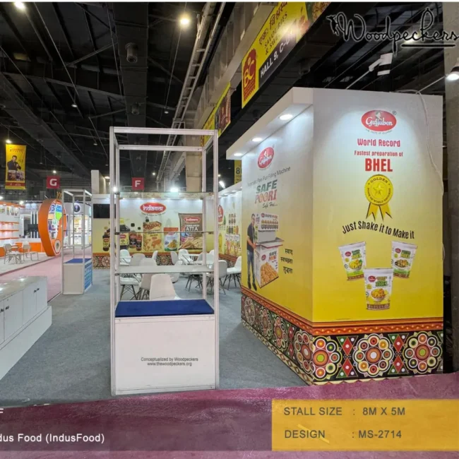 Trade show booth design by a top exhibition stall designer in Mumbai featuring Gujjuben branding, bold product graphics, interactive displays, and an open exhibition layout at Indus Food Expo.